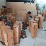 karyawan print merch sedang mengemas akrilik pesanan.